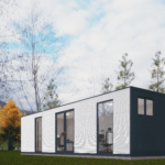 Bureau modulaire moderne avec extérieur blanc et lignes horizontales, grandes fenêtres et portes en verre avec cadres sombres, bureaux et chaises visibles à l'intérieur, situé dans une zone herbeuse avec des arbres aux couleurs automnales et un ciel partiellement nuageux.