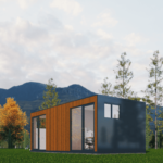 Bureau modulaire moderne avec une façade en bois et panneaux sombres, grandes fenêtres et portes vitrées, situé dans une zone herbeuse avec des arbres élancés et des montagnes en arrière-plan, sous un ciel partiellement nuageux. Intérieur visible avec des chaises et des bureaux modernes.
