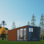 Bureau modulaire moderne avec panneaux extérieurs en bois et couleurs sombres, grandes portes coulissantes en verre et fenêtres, situé dans un environnement extérieur luxuriant avec de l'herbe bien entretenue et divers arbres, ciel clair et bleu.