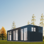 Bureau modulaire moderne avec grande fenêtres et portes en verre, situé dans une zone herbeuse avec des arbres en arrière-plan, ciel dégagé, meubles de bureau visibles à l'intérieur.