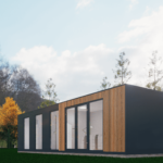 Maison modulaire moderne avec grandes fenêtres en verre et portes, panneaux sombres et lattes verticales en bois, située dans une zone herbeuse avec des arbres aux couleurs automnales en arrière-plan et un ciel partiellement nuageux.