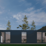 Bureau modulaire moderne avec façade extérieure sombre, grandes portes et fenêtres en verre, situé dans un cadre naturel avec des arbres élancés et un paysage montagneux en arrière-plan, sous un ciel partiellement nuageux.
