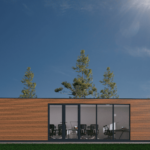 Bureau modulaire moderne avec façade en bois, grandes fenêtres en verre, chaises de bureau et tables visibles à l'intérieur, situé dans un cadre naturel avec des arbres élancés en arrière-plan et un ciel bleu clair.