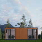 Bureau modulaire moderne avec façade en bois et grandes portes vitrées, situé dans une zone herbeuse avec des arbres et des montagnes en arrière-plan, sous un ciel partiellement nuageux.