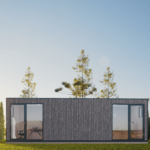 Bureau modulaire moderne avec façade en bois et grandes portes en verre, situé dans une zone herbeuse avec des arbres élancés en arrière-plan, ciel dégagé avec un léger ensoleillement, intérieur visible avec bureau et chaise.