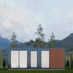 Maison modulaire moderne avec panneaux extérieurs gris et en bois, grandes fenêtres en verre, située dans une zone herbeuse avec de grands arbres et des montagnes en arrière-plan, sous un ciel partiellement nuageux. Intérieur visible avec des meubles modernes et fonctionnels.