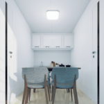 Cuisine minimaliste avec table en bois, deux chaises (une bleue et une grise), armoires blanches au mur, murs blancs, sol en bois clair et luminaire au plafond.